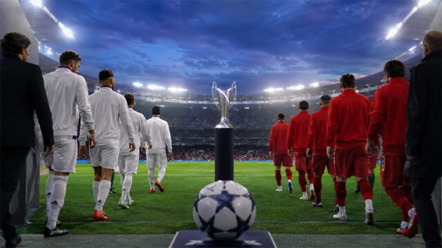 Dos equipos entran al campo, con un trofeo y un balón en primer plano
